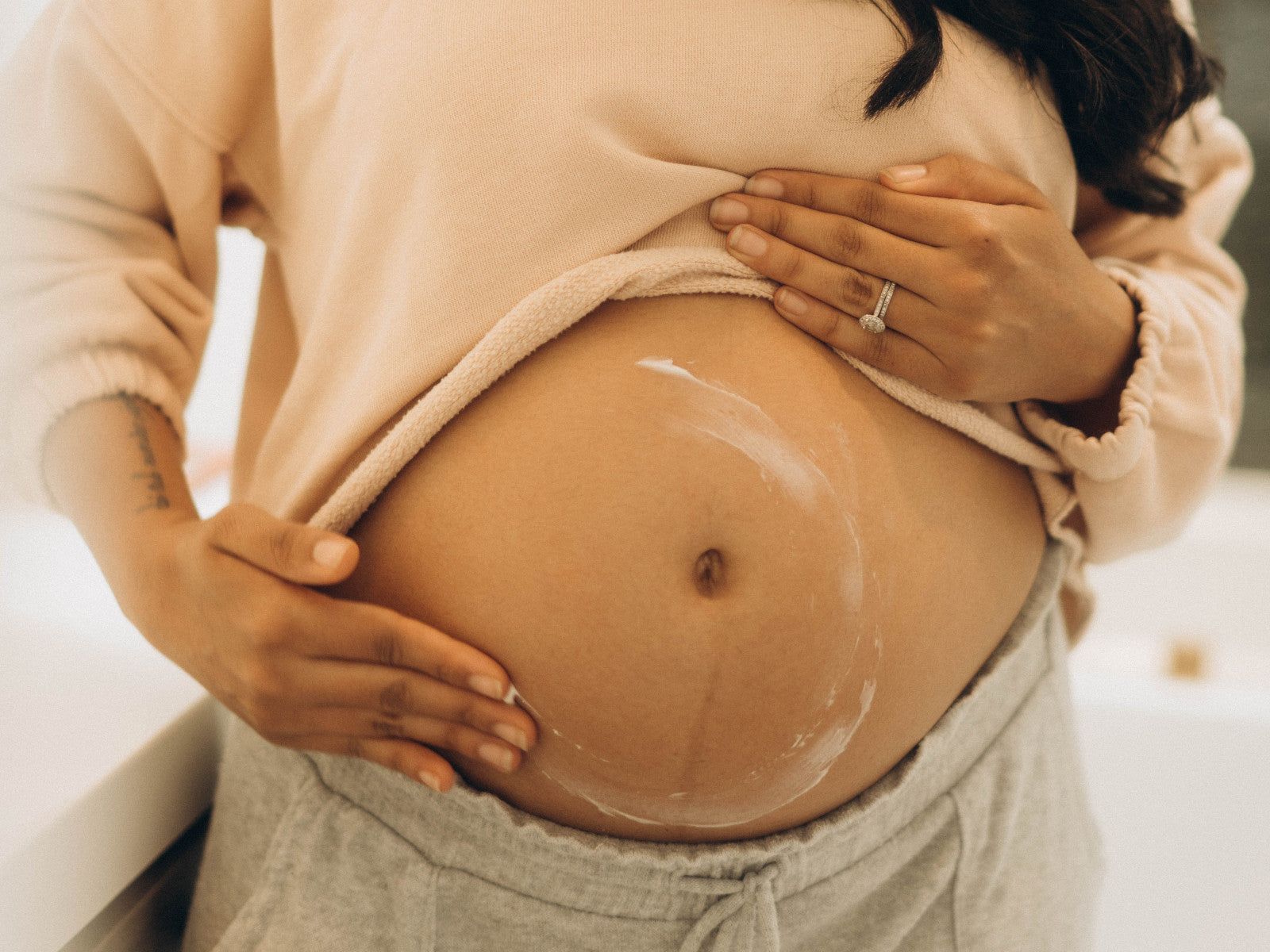 Pregnant woman applying cream to her bare belly in a close-up shot