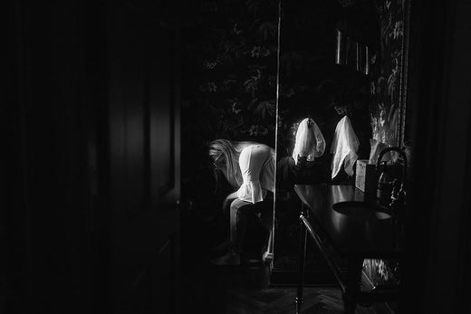 Black and white photo of a woman bent over in a dimly lit room, appearing to be unwell or nauseous, suggesting morning sickness.