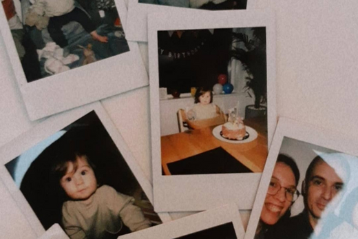 Several Polaroid photos scattered, including a child sitting at a table with a birthday cake and a photo of two adults smiling.