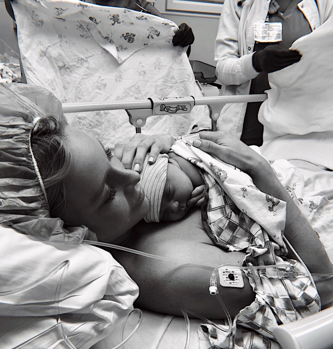 New mother holding her newborn skin-to-skin on her chest in an operating room after a Cesarean delivery