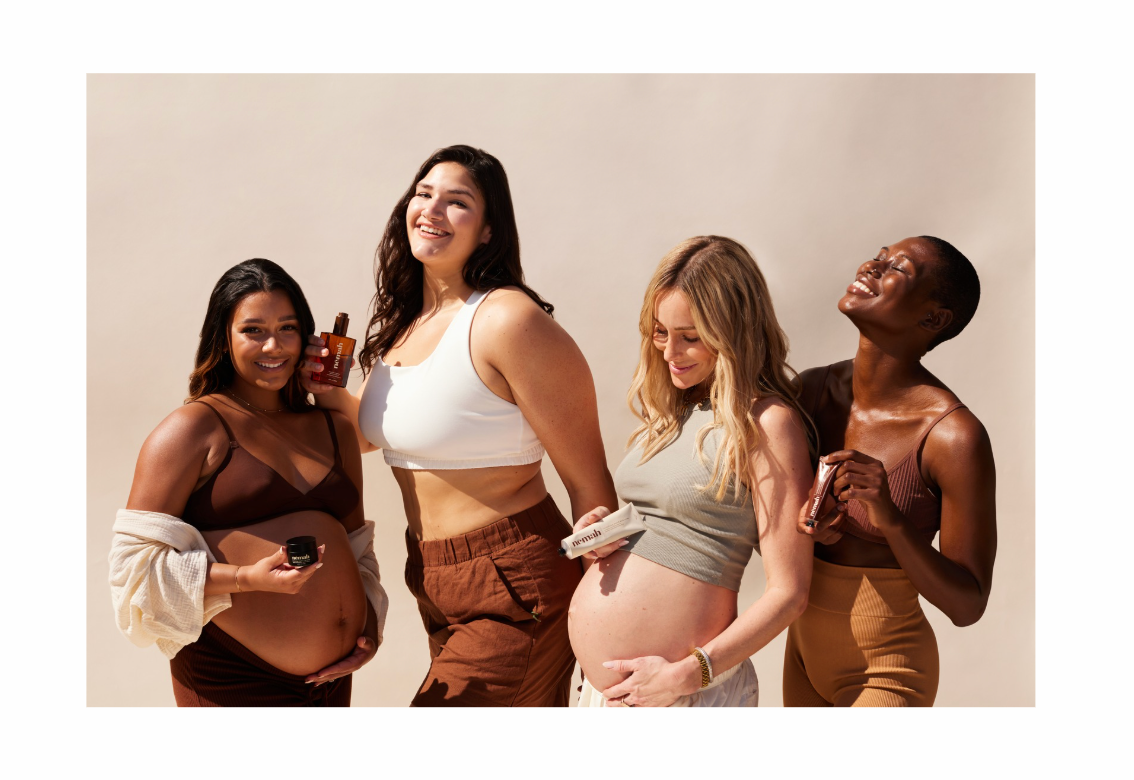 Four pregnant women smiling and posing together while holding Nēmah skincare products against a neutral studio backdrop
