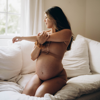 Pregnant woman is stretching on the bed