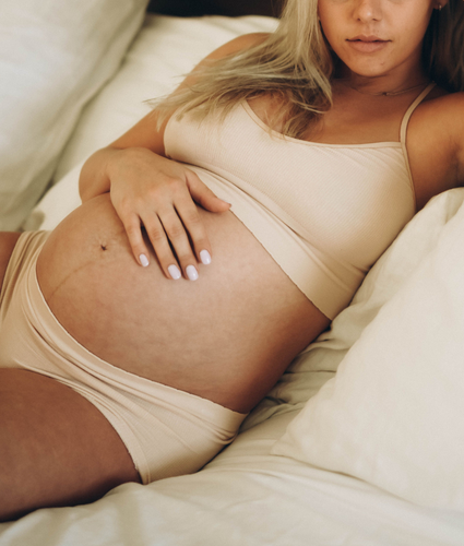 Pregnant woman is laying down on the bed