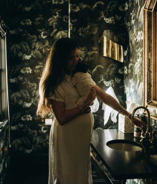 Pregnant person is holding a baby in the room
