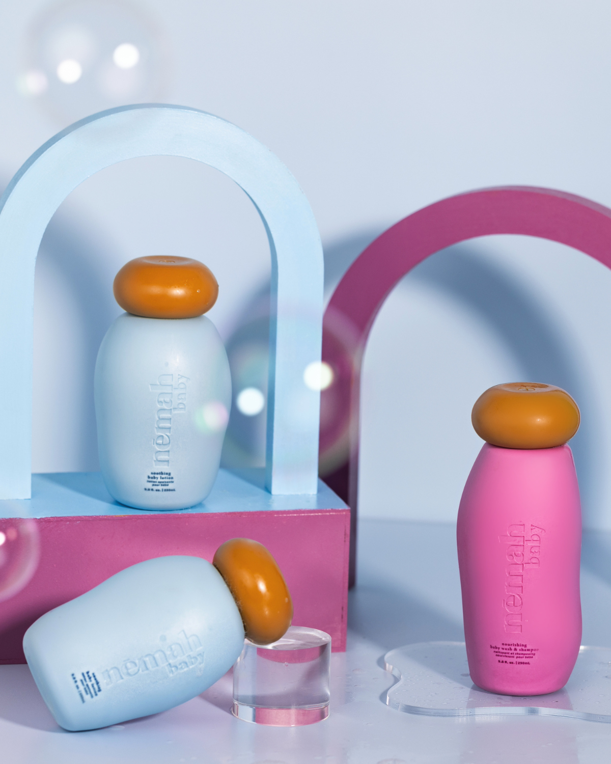 Three bottles of baby shampoo and lotion arranged with a colorful background, featuring soft, ultra-gentle formulas for baby care