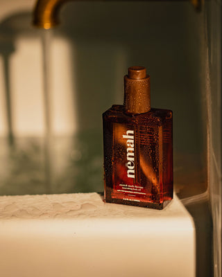 Brown glass bottle with water droplets labeled 'nemah'; reads 'stretch mark therapy', 'nourishing body oil', '3.4 fl. oz. | 100mL'.