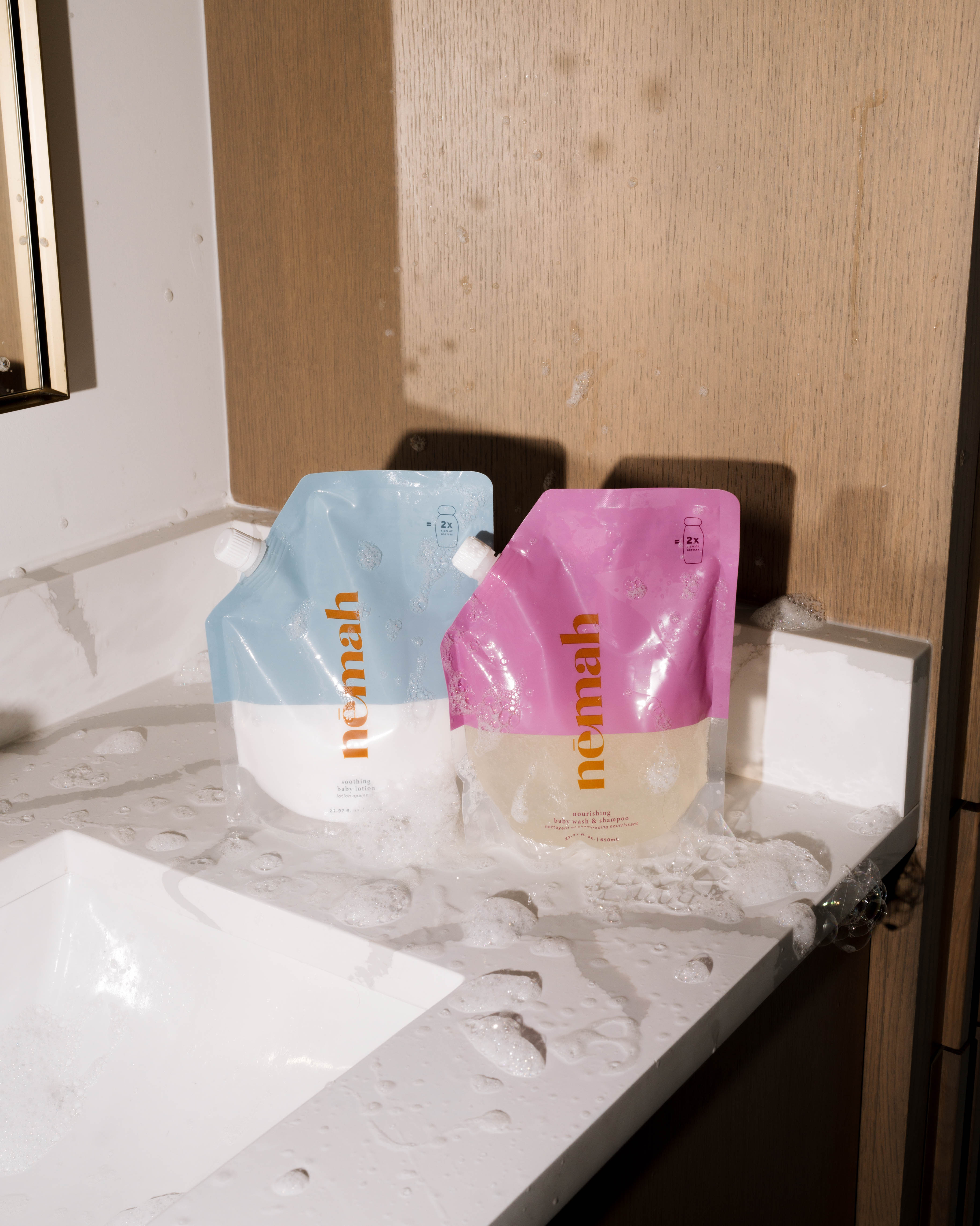 Two product pouches on a wet bathroom counter.