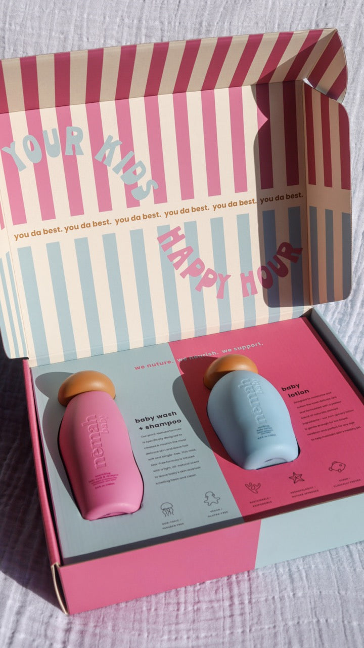 A bottle of baby wash shampoo and baby lotion inside a striped box with 'Your Kid's Happy Hour' text