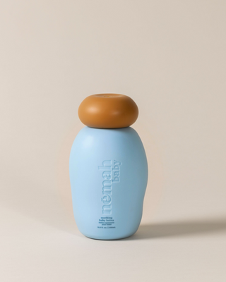 Blue bottle with a rounded brown cap labeled "nēmah baby" with text "soothing baby lotion lotion apaisante pour bébé 5.0 fl. oz. | 150 mL"