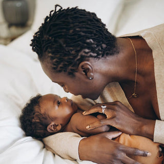 Person lovingly holding a baby on a bed.