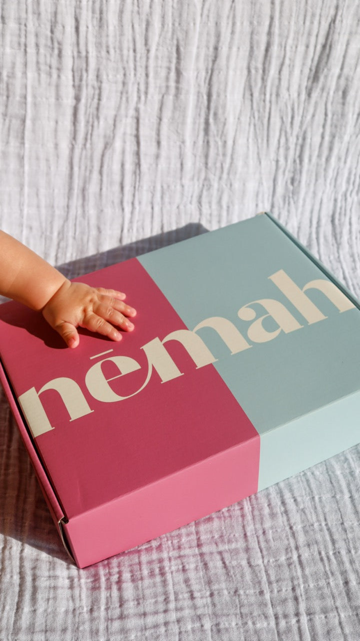 Baby's hand touching a 'nemah' branded box.