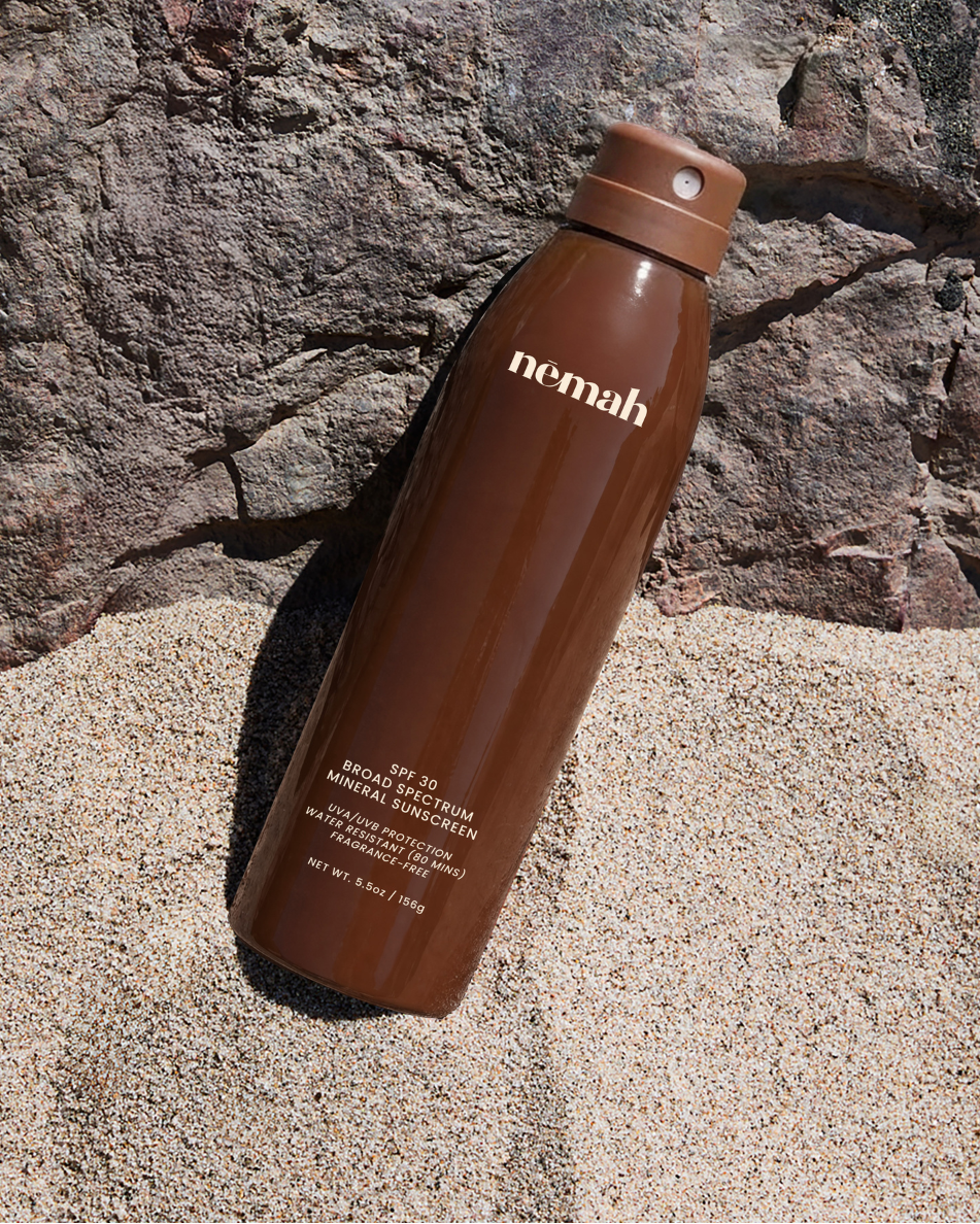 Brown water bottle with 'nemah' branding on a rocky surface