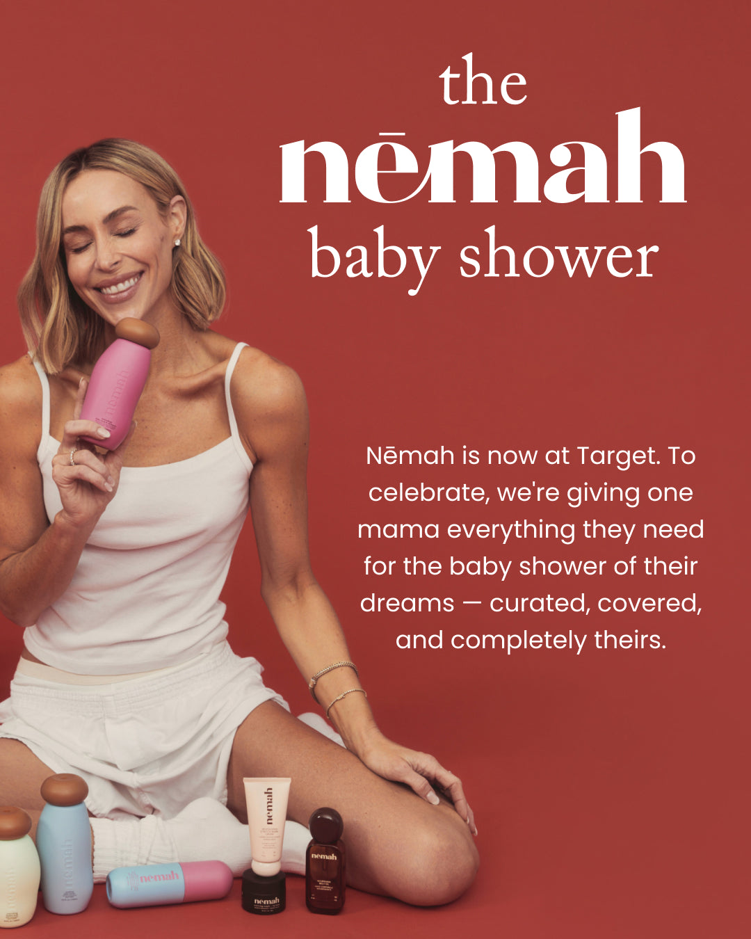 Smiling woman holding a pink Nēmah bottle with Nēmah products at her feet, headline the nēmah baby shower on terracotta background