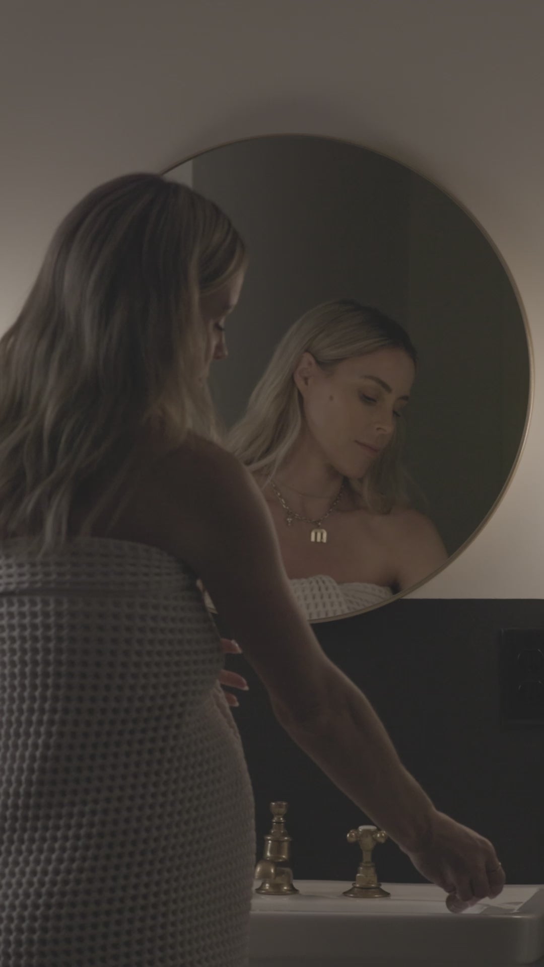 Person in a bathroom adjusting a faucet.