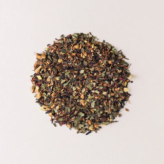 Loose dried tea leaves and herbs arranged in a circular pile on a light background